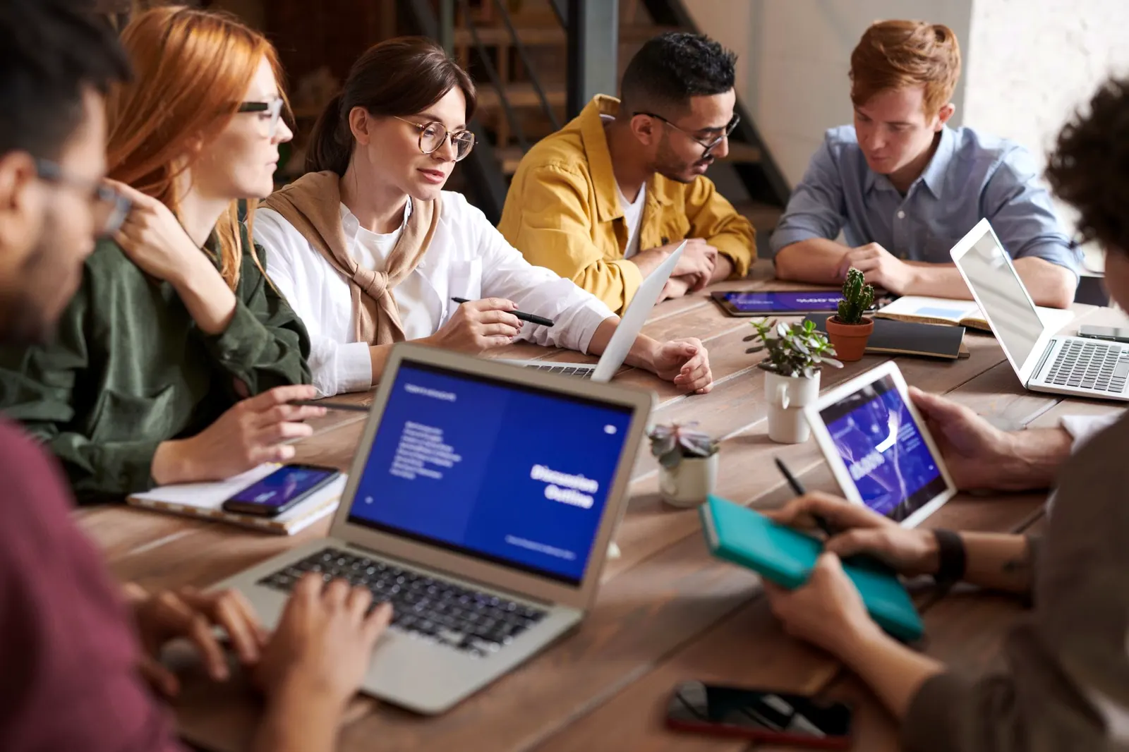Un grupo de emprendedores conversa alrededor de una mesa de trabajo